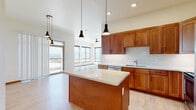 This single-floor residence at 2226 E Philadelphia Street in Rapid City, South Dakota, offers a well-designed open-concept layout with thoughtful finishes throughout. The kitchen serves as the centerpiece of the living space, showcasing warm wood cabinetry, a classic white subway tile backsplash, light quartz countertops, and a generously sized center island illuminated by a trio of modern black pendant lights. Stainless steel appliances, including a refrigerator, range, and microwave, complete the functional kitchen setup. Light hardwood-style flooring runs throughout the main living and kitchen areas, creating a cohesive, airy feel.

The living area benefits from an abundance of natural light streaming through large windows, which frame expansive outdoor views. A ceiling fan and recessed lighting add comfort and practicality. Sliding doors provide direct access to a private balcony. The bedroom features plush carpeting and connects to a private bathroom equipped with a full soaking tub and wood vanity. An in-unit laundry area accommodates a full-size washer and dryer, adding everyday convenience. The overall ambiance is clean, modern, and bright.