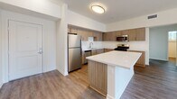 Located at 30135 Rancho California Rd in Temecula, CA, this modern single-floor residence combines clean design with functional living. The open-concept layout connects the kitchen, dining, and living areas seamlessly, creating a bright and airy atmosphere. The kitchen is well-appointed with wood-grain cabinetry, quartz countertops, a large kitchen island, a double basin stainless steel sink, and a full suite of stainless steel appliances including a refrigerator, gas range, microwave, and dishwasher. The living and dining areas feature warm wood-look flooring and are illuminated by a stylish chandelier, adding an elegant touch to the space. Multiple bedrooms offer natural light through wide windows with views of the surrounding landscape, complemented by the same durable wood-look flooring. The primary bathroom includes a full soaking tub and shower combination with classic white subway tile, built-in shelving, and a modern vanity. A secondary half-bath provides added convenience with a clean, contemporary vanity and natural light from a window. Throughout the residence, neutral tones and modern fixtures create a cohesive and inviting aesthetic.