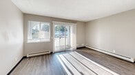 Located at 7650 40th St W in University Place, Washington, this single-floor residence showcases a thoughtfully updated interior with a clean, modern aesthetic throughout. Durable wood-style flooring runs continuously across the living areas, complemented by neutral-toned walls and dark baseboards that lend a polished, cohesive look.

The bright living area is a standout feature, benefiting from generous natural light streaming through a large window and sliding glass doors that open onto a private balcony, offering pleasant outdoor views. Baseboard heating units are present throughout, ensuring consistent comfort.

The kitchen is well-appointed with rich dark wood cabinetry, white subway tile backsplash, light stone-look countertops, and a full suite of stainless steel appliances including a refrigerator, range, microwave, and dishwasher. Recessed lighting adds a refined touch overhead.

The bedroom is comfortably sized with a natural light source and baseboard heating. A five-panel interior door adds a stylish architectural detail. The bathroom features a dual-sink vanity with dark wood cabinetry, a white countertop, and a tiled tub-shower combination.

A dedicated laundry area with a stacked washer and dryer unit, alongside wire shelving, adds practical functionality to this well-rounded space.