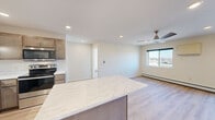 Located at 845 Ash St in Clearwater, MN, this well-appointed one-bedroom, one-bathroom unit offers a thoughtfully designed single-floor layout. The open-concept kitchen and living area serves as the heart of the home, featuring light hardwood-style flooring, recessed lighting, and a ceiling fan. The kitchen is outfitted with taupe shaker-style cabinetry, stainless steel appliances including a refrigerator, dishwasher, and range, along with a double-basin sink and quartz countertops that extend to a generous center island — ideal for casual dining or meal prep. The living area receives natural light through a large window and offers access to a private balcony through a sliding glass door. The bedroom is carpeted and bright, benefiting from multiple windows that bring in ample natural light, complemented by baseboard heating. A spacious walk-in closet with built-in wire shelving provides generous storage. The bathroom features hardwood-style flooring, a warm wood vanity, baseboard heating, and grab bars, reflecting an accessible and practical design. Throughout, neutral tones and clean finishes create a cohesive, move-in-ready atmosphere.