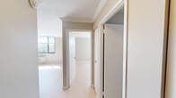 Located at 360 Main St in Hartford, CT, this one-bedroom, one-bathroom residence offers a well-organized single-floor layout designed to maximize every square foot. The space is finished with light hardwood-style flooring, crown molding, and a neutral warm-gray color palette throughout, creating a clean and cohesive aesthetic.

The kitchen is a standout feature, outfitted with sleek gray flat-front cabinetry extending to the ceiling, dark countertops, a stainless steel sink, a built-in oven, microwave, refrigerator, and a conveniently integrated in-unit washer. A central island provides additional prep and dining surface area.

The bedroom is a comfortably sized, sun-filled room featuring a large window with city views, light-toned flooring, crown molding, and a built-in closet with sliding doors. A second closet is also available within the unit for additional storage.

The bathroom is modern and refined, featuring a wall-mounted floating vanity with an integrated sink, a framed medicine cabinet mirror, and a full glass-enclosed walk-in shower with large-format tile surround and built-in shelving. Black matte hardware accents add a contemporary touch.

A hallway connects all rooms efficiently, with the open layout visible from the entry. The unit receives generous natural light, contributing to its bright and airy atmosphere.