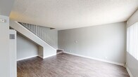 Located at 1718 Ximeno Ave in Long Beach, California, this two-story space offers a practical and well-appointed layout with consistent finishes throughout. The main living area on the ground floor features durable wood-look flooring, neutral gray walls, and a textured ceiling. A staircase with a metal railing connects the two levels, making efficient use of the vertical space. A ceiling fan with a light fixture provides both airflow and illumination in the primary living area, which benefits from a large window dressed with vertical blinds that invite natural light.

The kitchen is thoughtfully outfitted with warm wood cabinetry, white countertops, a double-basin sink, a gas range, and a stainless steel refrigerator, offering ample storage and functional workspace. An adjacent open area with its own window and wall-unit air conditioning provides flexible use as a dining or secondary living space.

The bedrooms are comfortable and well-lit, each featuring wood-look flooring, ceiling fans, and windows with vertical blinds. One bedroom includes a mirrored sliding-door closet with built-in shelving, maximizing storage. The bathroom is clean and bright, with a tub-shower combination, a vanity with a single sink, white countertops, and matching wood cabinetry consistent with the kitchen's design. The overall aesthetic is clean, neutral, and move-in ready.