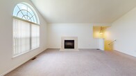 Located at 2427 Partridge Dr in Shelby Township, MI, this 2-bedroom, 2-bathroom home offers a well-designed single-floor layout. The open-concept living and kitchen area serves as the heart of the home, featuring vaulted ceilings that enhance the sense of space. The living room includes a tile-surround fireplace and flows seamlessly toward a staircase entry with a decorative pendant light overhead. The kitchen is outfitted with warm wood cabinetry, granite countertops, stainless steel appliances including a refrigerator, range, and microwave, and a breakfast bar that connects to the living space. Light hardwood-style flooring anchors the kitchen, while plush carpet runs through the living areas and bedrooms. The primary bedroom is generously sized, featuring vaulted ceilings and a large arched window that fills the room with natural light and outdoor views. The second bedroom also enjoys natural light through a bright window. Both bathrooms are finished with granite vanity tops and tile flooring; one includes a tub with sliding glass doors. A dedicated laundry room with side-by-side washer and dryer adds everyday convenience, completing this functional and comfortable home.