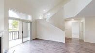 This two-story residence on Wesley Place in Lawrenceville, Georgia offers a clean, neutral aesthetic throughout, with thoughtful design details across both levels. The main living area immediately impresses with its soaring vaulted ceilings and an abundance of natural light streaming through transom and arched windows positioned high on the walls. Smooth hardwood-style flooring runs through the main level, complementing the bright, white walls and crisp baseboards. A sliding glass door connects the living area to an outdoor space, enhancing the sense of openness. A staircase with a clean white railing leads to the upper level.

The kitchen is well-appointed, featuring white shaker-style cabinetry, granite countertops, a subway tile backsplash, and stainless steel appliances including a refrigerator and electric range. A peninsula with an undermount sink adds functional prep and dining space.

The bedrooms are carpeted for comfort, each finished in soft neutral tones with windows that bring in natural light. The bathrooms are outfitted with white tile surround tub-shower combinations and chrome fixtures, maintaining the home's consistent, clean design language throughout.