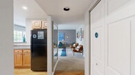 This 2-bedroom, 1-bathroom residence offers a thoughtfully designed single-floor layout that balances comfort and functionality. The entry hallway leads into a galley-style kitchen outfitted with warm honey-toned wood cabinetry, dark granite-style countertops, hardwood flooring, and full appliances including a gas range and black refrigerator. The kitchen opens seamlessly into a bright dining area bathed in natural light from a large window, creating an inviting space for everyday meals. Adjacent to the dining area, the living room makes a strong visual impression with a bold gray accent wall, carpet flooring, and ample space for comfortable seating arrangements. The primary bedroom is generously proportioned, featuring a gray accent wall, soft carpet, a large window with outdoor views, and a spacious closet. The second bedroom provides comparable comfort with its own closet and neutral finishes. The full bathroom is cleanly finished with white subway tile surrounding a full tub-shower combo, a wood-toned vanity, and chrome fixtures. A dedicated closet and hallway round out the layout, providing practical storage and easy circulation throughout the home. The overall aesthetic is cohesive and modern, with consistent neutral tones accented by warm wood finishes throughout.