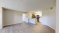 This single-story, 2-bedroom, 2-bathroom residence offers a practical and well-designed layout with consistent wood-look flooring and neutral warm-gray tones throughout. The open-concept living and kitchen area serves as the heart of the home, with the spacious living room featuring a ceiling fan, textured ceiling, and wide windows that allow natural light to fill the space. The kitchen is thoughtfully equipped with white shaker-style cabinetry, a light marble-look countertop peninsula with an integrated sink, subway tile backsplash, and a full suite of stainless steel appliances including a gas range, microwave, refrigerator, and dishwasher. Both bedrooms are comfortably sized, each featuring ceiling fans, wood-look flooring, and windows with outdoor views. The primary bedroom includes access to a dedicated closet. Both bathrooms are finished in a clean, neutral palette and feature full tub-shower combinations with white tile surrounds, vanities with marble-look countertops, and wood-look flooring. Additional storage is provided by two closets found throughout the unit. The overall ambiance is clean, bright, and move-in ready, reflecting a cohesive and modern aesthetic across all rooms.
