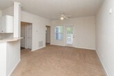 Located on Walden Brook Drive in Lithonia, Georgia, this single-floor residence offers a practical and comfortable layout designed for easy living. The main living area is generously sized, featuring warm neutral-toned carpet, crown molding, and a ceiling fan with a light fixture — adding both function and a polished finish to the space. A pass-through opening connects the living area to the kitchen, promoting an open feel and ease of interaction between the two spaces. The kitchen follows a galley-style layout with white cabinetry, laminate countertops, dark hardwood-style flooring, and white appliances including a refrigerator and electric range. A paneled interior door leads to additional storage or utility access. The bedrooms continue the carpet flooring and neutral wall palette, with one room featuring a large window that brings in abundant natural light and views of the surrounding greenery. Textured ceilings are present throughout the home. The bathroom is clean and functional, offering a tiled tub-and-shower combination, a toilet, vanity with sink, and a mirror — all finished in crisp white tones. The overall ambiance of the home is bright, clean, and move-in ready, offering a straightforward and welcoming environment in a residential Lithonia community.