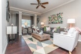 Located in Athens, GA, this single-floor residence offers a thoughtfully designed open-concept layout with modern finishes throughout. The kitchen is a standout feature, showcasing granite countertops, gray shaker-style cabinetry, a subway tile backsplash, stainless steel appliances, and pendant lighting above a generous island — ideal for both everyday cooking and entertaining. The living area is anchored by rich, dark hardwood flooring and features crown molding, a ceiling fan, and natural light streaming in through large windows with drapery. Decorative columns subtly define the transition between the living and dining spaces, adding an architectural touch. A cozy secondary sitting area connects seamlessly to the main living room, offering additional flexibility. The bathroom is well-appointed with granite countertops, gray cabinetry, a single undermount sink, brushed nickel fixtures, and a shower-tub combination. A dedicated laundry closet provides added convenience. The hallway connecting the rooms is clean and functional, with access to the bathroom and additional storage. Neutral warm-gray walls throughout create a cohesive and inviting ambiance, complementing the contemporary design elements that define this comfortable Athens residence.