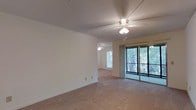 This single-story, 3-bedroom, 2-bathroom home offers a well-designed layout that maximizes comfort and functionality. The open living area features plush wall-to-wall carpeting, neutral-toned walls, and a textured ceiling, creating a clean and welcoming atmosphere. A ceiling fan with integrated lighting keeps the space comfortable year-round while adding a practical touch to the room's design. Large sliding glass doors flood the living area with abundant natural light and provide direct views of the surrounding lush, tree-lined greenery, seamlessly connecting the interior to the outdoors. The open sightline into the adjoining room further enhances the sense of spaciousness throughout the home. The layout flows naturally between living, sleeping, and bathroom spaces, offering a practical and cohesive floor plan suited for everyday living. With three well-proportioned bedrooms and two full bathrooms, this home accommodates a variety of lifestyle needs. The consistent use of neutral finishes and soft carpeting throughout contributes to a calm, unified aesthetic, making the space easy to personalize and furnish to individual taste.