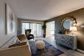 Located at 4907 Cloverlane Dr in Ypsilanti, Michigan, this well-appointed two-bedroom, two-bathroom single-floor home offers a thoughtfully designed layout across a comfortable footprint. The living room serves as the heart of the space, featuring wood-style flooring, a textured ceiling, and bold accent walls in deep gray that create a stylish, contemporary atmosphere. Large sliding glass doors flood the room with natural light while providing direct access to an outdoor patio area. The adjacent dining area continues the light-filled theme with a generous window overlooking greenery outside. The kitchen is outfitted with white shaker cabinetry, stone-look countertops, a subway tile backsplash, stainless steel appliances, and a peninsula with a built-in sink — ideal for both cooking and casual dining. The primary bedroom offers a serene retreat with plush carpeting and a warm, neutral palette, while the second bedroom provides a cozy, versatile space with carpet flooring. Both bathrooms feature white vanity cabinetry, granite-style countertops, and wood-look tile flooring. With four closets and a dedicated utility room, storage is abundant throughout. The home's cohesive modern design and functional layout make it a highly practical and inviting residence.