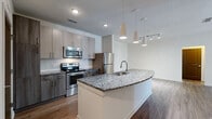 Located at 2439 Casona Ln in Melbourne, Florida, this single-floor residence offers a well-designed open-concept layout with contemporary finishes throughout. The kitchen serves as a central highlight, featuring a large granite-topped island with an integrated sink, stainless steel appliances including a range, microwave, and refrigerator, complemented by modern cabinetry and stylish pendant lighting. The kitchen flows seamlessly into the living area, which is finished with rich wood-style flooring and benefits from natural light through glass panel doors that open to the exterior. A ceiling fan adds comfort to the living space. The bedrooms are carpeted for warmth and comfort, each offering windows with blinds that allow for natural light and privacy. The primary suite includes a spacious walk-in closet outfitted with multi-level wire shelving for generous storage. The bathrooms are appointed with granite countertops, modern cabinetry, and wood-style flooring. The primary bathroom features a dual-sink vanity with a large mirror, while the secondary bathroom includes a full tub and shower combination. Throughout the residence, neutral tones, clean lines, and consistent finishes create a cohesive and inviting atmosphere.