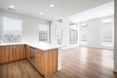 Located at 3852 E Warm Springs Ave in Boise, Idaho, this two-story residence showcases a clean, contemporary design with consistent, high-quality finishes throughout. The main living area features an open-concept layout where the kitchen flows seamlessly into the living space. Soaring ceilings with clerestory windows and a glass-paneled exterior door flood the area with natural light, while light-toned hardwood flooring unifies the space. The kitchen is well-appointed with stainless steel appliances, white upper cabinetry, warm wood-grain lower cabinets, and a quartz waterfall-edge island. A window above the sink provides views of the surrounding neighborhood.

The bathrooms continue the home's modern aesthetic, each featuring wood-grain cabinetry, white quartz countertops, and light hardwood flooring. One bathroom includes a walk-in glass shower, while another offers a tub-shower combination with a tall storage tower. Bedrooms are finished with plush carpet and include sliding-door closets with built-in shelving. One bedroom features tall windows with transom accents, maximizing natural light. A dedicated laundry room houses a stacked washer and dryer alongside additional cabinetry and counter space, completing this well-organized and thoughtfully designed home.