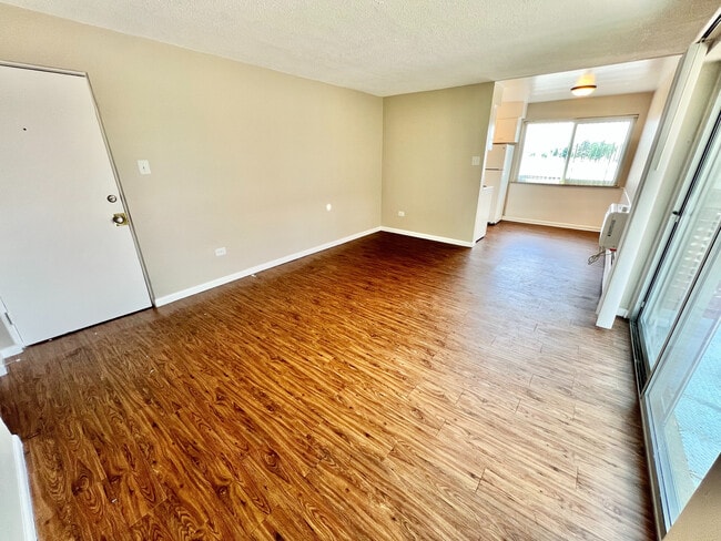 Bright and airy living space with stylish wood flooring, large windows, and an open layout perfect for modern living. - Bonneville Apts