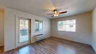 This single-story unit on Matzen Street in Saint Helens, Oregon, offers a well-designed layout with consistent wood-look flooring flowing throughout the living areas and bedrooms. The living room serves as a welcoming central space, featuring a ceiling fan with integrated lighting, a wall-mounted HVAC unit, and multiple windows that bring in generous natural light. A glass exterior door provides direct outdoor access and adds to the bright, open feel of the room.

The kitchen is designed for functionality, featuring a galley-style layout with warm wood cabinetry, granite-style countertops, an undermount sink, and a full suite of black appliances including a refrigerator, electric range, microwave, and dishwasher. Upper and lower cabinets provide ample storage, and the space connects conveniently to additional storage and the rest of the unit.

The bedrooms continue the wood-look flooring and are naturally lit by well-placed windows with blinds. Each room includes ceiling fans and wall heating units for comfort year-round.

Two bathrooms serve the unit, each finished with warm wood vanities, granite-style countertops, and light tile flooring. One bathroom features a soaking tub and shower combination, while the other includes a walk-in shower, offering practical flexibility for residents.
