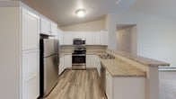 Located at 6905 Schofield Ave in Weston, Wisconsin, this single-floor unit offers a thoughtfully designed layout that balances comfort and functionality. The open-concept kitchen and living area serves as the heart of the space, where crisp white shaker-style cabinetry, granite-style countertops, and a full suite of stainless steel appliances — including a refrigerator, range, and over-the-range microwave — create a clean, modern aesthetic. A breakfast bar peninsula connects the kitchen to the adjoining living area, which features wood-look flooring and a ceiling fan overhead. The living space transitions into a carpeted area, offering a cozy retreat with baseboard heating and access to a patio or balcony via sliding glass doors. The bedrooms are carpeted and well-lit by natural light through window blinds, each equipped with closet storage. Two bathrooms serve the unit, both featuring wood-look flooring, white cabinetry, granite-style vanity countertops, and large mirrors. One bathroom includes a walk-in shower, while the other provides additional storage with a tall cabinet. The overall palette of neutral tones and white trim lends the space a bright, move-in-ready feel throughout.