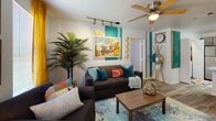 Located at 1952 Heritage Grove Cir in Tallahassee, FL, this single-floor residence offers a thoughtfully designed layout with a lively and eclectic aesthetic throughout. The living area is a standout space, featuring bold teal accent walls, a Florida-themed mural, track lighting, a ceiling fan, and wood-look flooring. Comfortable seating, vibrant throw pillows, and warm natural light from large windows with golden drape accents create a welcoming, personality-filled atmosphere. The kitchen is well-appointed with gray shaker-style cabinetry, stainless steel appliances including a refrigerator, range, microwave, and dishwasher, and striking marble-look countertops. A peninsula with bar seating adds functionality and a casual dining option. The bedrooms are carpeted and bright, each with a ceiling fan, natural light from windows, and distinct design touches — one featuring warm earthy tones and a dedicated workspace, another with a bold botanical theme. The bathrooms are finished with gray vanities, marble-look countertops, and wood-look flooring, each showcasing unique decorative wall arrangements. This home blends practical living features with a cohesive, vibrant design sensibility throughout every room.