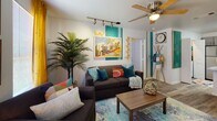 Located at 1952 Heritage Grove Cir in Tallahassee, FL, this single-floor residence offers a thoughtfully designed layout with a lively and eclectic aesthetic throughout. The living area is a standout space, featuring bold teal accent walls, a Florida-themed mural, track lighting, a ceiling fan, and wood-look flooring. Comfortable seating, vibrant throw pillows, and warm natural light from large windows with golden drape accents create a welcoming, personality-filled atmosphere. The kitchen is well-appointed with gray shaker-style cabinetry, stainless steel appliances including a refrigerator, range, microwave, and dishwasher, and striking marble-look countertops. A peninsula with bar seating adds functionality and a casual dining option. The bedrooms are carpeted and bright, each with a ceiling fan, natural light from windows, and distinct design touches — one featuring warm earthy tones and a dedicated workspace, another with a bold botanical theme. The bathrooms are finished with gray vanities, marble-look countertops, and wood-look flooring, each showcasing unique decorative wall arrangements. This home blends practical living features with a cohesive, vibrant design sensibility throughout every room.