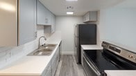 This two-floor residence presents a clean, contemporary aesthetic achieved through thoughtful updates across every room. Gray-toned luxury vinyl plank flooring runs consistently throughout the living areas, bedrooms, and bathrooms, providing a cohesive and low-maintenance foundation. Textured ceilings and crisp white trim complement the neutral wall tones, creating a bright and airy atmosphere.

The kitchen is well-appointed with slate-blue cabinetry featuring brushed nickel hardware, white quartz-style countertops, a classic subway tile backsplash, and stainless steel appliances including a refrigerator and range. A double-basin sink with a brushed nickel faucet adds functional detail.

The bedrooms are generously proportioned, each offering built-in closet shelving and hanging rods. Natural light enters through windows fitted with horizontal blinds, while one bedroom features a sliding glass door opening to an outdoor view.

The bathrooms are neatly finished with light blue or neutral vanity cabinetry, white countertops, framed mirrors, and updated lighting fixtures. One bathroom includes a full tub and shower combination. Throughout the space, clean lines, consistent finishes, and abundant natural light contribute to a fresh, move-in-ready environment.