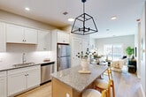 Located at 150 Draper Ave in North Attleborough, MA, this well-appointed one-bedroom, one-bathroom residence offers a smart, efficient layout across a single floor. The open-concept kitchen and dining area serves as the heart of the home, showcasing white shaker cabinetry, subway tile backsplash, stainless steel appliances, and a granite-topped island illuminated by a striking black geometric pendant light. Light hardwood flooring flows throughout, complementing the neutral, warm palette. The living room is bright and inviting, anchored by a large sliding glass door that opens to a private patio and fills the space with natural light. The bedroom is a comfortable retreat, featuring a double closet, natural light from a sizable window, and warm wood-toned accents. Additional storage is well-addressed with four closets throughout the unit. A dedicated office provides a quiet workspace, while the hallway leads to a clean, modern bathroom finished with granite countertops and hardwood-style flooring. In-unit laundry and a utility room add everyday convenience. The overall ambiance is contemporary and calm, with a cohesive design language that balances functionality and modern style throughout.