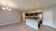 This single-floor residence offers a thoughtfully designed open-concept layout with consistent, modern finishes throughout. Light wood-tone flooring runs seamlessly across the main living areas, complemented by neutral gray and taupe wall tones that create a clean, cohesive aesthetic.

The kitchen is a standout feature, equipped with rich dark espresso cabinetry, granite countertops, and a full suite of stainless steel appliances including a refrigerator, electric range, and built-in microwave. A center island with a granite surface and undermount sink adds both functionality and style, with pendant lighting above enhancing the space. Recessed lighting and direct sightlines to the main entry make this area feel open and connected.

The living and dining areas are generously proportioned, with the dining space showcasing an elegant chandelier and a sliding glass door that brings in natural light. The main living area features recessed lighting and a large window for additional brightness.

The primary bedroom includes dual windows with blinds, a ceiling fan, a walk-in closet, and a private en-suite bathroom. The en-suite is well-appointed with a double-sink granite vanity, dark cabinetry, dual oval mirrors, and a shower/tub combination. A second bathroom features a single granite vanity with dark cabinetry and tile flooring, conveniently accessible from the hallway.