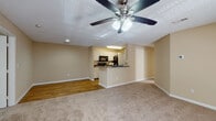 This single-story residence is designed with a practical, open-concept layout that connects the living area and kitchen in a cohesive, functional space. The living area features plush neutral carpet, warm beige walls, and a ceiling fan with integrated lighting, creating a comfortable and welcoming environment. A textured ceiling adds subtle visual interest throughout the common areas.

The kitchen is configured in a galley style, offering ample cabinetry with white cabinet fronts, granite-look countertops, and black appliances including a refrigerator, range, microwave, and dishwasher. Wood-look flooring runs the length of the kitchen, and a peninsula counter separates it from the living space, providing a convenient serving or dining area.

Both bedrooms are generously proportioned, finished with soft carpet, neutral walls, ceiling fans, and windows fitted with blinds that allow natural light while maintaining privacy. Each room includes closet access and multiple electrical outlets for flexibility.

The two bathrooms mirror each other in design, each featuring a vanity with a granite-look countertop, an undermount sink, white cabinetry, wood-look flooring, and a shower-tub combination with a curtain rod. The overall aesthetic of the unit is clean, neutral, and move-in ready.