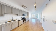 Located on the iconic Sunset Boulevard in Los Angeles, this thoughtfully designed one-bedroom, one-bathroom residence offers a clean, modern aesthetic throughout. Light-toned hardwood-style flooring runs across the open-concept main living area, connecting the kitchen and living room in a seamless, airy flow. The kitchen is well-appointed with grey shaker-style cabinetry extending to the ceiling for ample storage, bright white countertops, a stainless steel refrigerator, range, microwave, and dishwasher — providing a full suite of appliances for everyday living. Track and flush-mount lighting illuminate the space efficiently. The living area is bright and open, with natural light streaming through windows and a glass-paneled door. The spacious bedroom is carpeted for comfort and features a large window framing picturesque views of the surrounding Los Angeles hills and cityscape. The full bathroom includes a single vanity with white countertop, a tiled soaking tub and shower combo, and a conveniently integrated in-unit stacked washer and dryer. The unit's clean white walls and consistent finishes throughout create a fresh, move-in ready environment suited for comfortable urban living in one of LA's most sought-after neighborhoods.