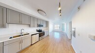 Located on the iconic Sunset Boulevard in Los Angeles, this thoughtfully designed one-bedroom, one-bathroom residence offers a clean, modern aesthetic throughout. Light-toned hardwood-style flooring runs across the open-concept main living area, connecting the kitchen and living room in a seamless, airy flow. The kitchen is well-appointed with grey shaker-style cabinetry extending to the ceiling for ample storage, bright white countertops, a stainless steel refrigerator, range, microwave, and dishwasher — providing a full suite of appliances for everyday living. Track and flush-mount lighting illuminate the space efficiently. The living area is bright and open, with natural light streaming through windows and a glass-paneled door. The spacious bedroom is carpeted for comfort and features a large window framing picturesque views of the surrounding Los Angeles hills and cityscape. The full bathroom includes a single vanity with white countertop, a tiled soaking tub and shower combo, and a conveniently integrated in-unit stacked washer and dryer. The unit's clean white walls and consistent finishes throughout create a fresh, move-in ready environment suited for comfortable urban living in one of LA's most sought-after neighborhoods.