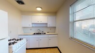Located at 4550 Hilton Ave in Columbus, Ohio, this single-floor unit offers a straightforward and functional layout across several distinct spaces. The kitchen features white cabinetry — both upper and lower — with ample storage, a stainless steel double-basin sink, light countertops, a white gas range, and tile flooring. A window with blinds allows natural light to brighten the space. The living area is carpeted with dark baseboards and neutral walls, with a sliding glass door providing access and additional light. A dedicated bedroom continues the carpeted flooring and neutral palette, with a window fitted with blinds that offers an outdoor view. An additional room, also carpeted, connects through to the kitchen area, lending flexibility to the floor plan. The full bathroom is equipped with a vanity and sink with a mirrored medicine cabinet, a toilet, and a bathtub and shower combination with surrounding panels and a privacy window. Tile flooring completes the bathroom. Throughout the unit, the design is clean and utilitarian, with consistent neutral tones and practical finishes that provide a functional living environment.
