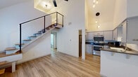 Located at 305 E 4th St in the heart of Austin, TX, this two-story, one-bedroom, one-bathroom home offers a smart and efficient layout spread across two distinct levels. The main floor is anchored by a dramatic open-concept living area with soaring ceilings that amplify the sense of space and airiness. Light wood-tone flooring flows throughout, complementing the bright white walls and creating a clean, contemporary aesthetic. A sleek open-riser staircase with a modern cable-and-wood railing serves as both a functional and architectural focal point, leading to the upper loft level. Pendant lighting with Edison-style bulbs adds warmth and character to the space. The well-appointed kitchen features white shaker-style cabinetry, dark granite countertops, stainless steel appliances including a range, refrigerator, microwave, and dishwasher, along with a double-basin sink and task lighting. A hallway off the main living area leads to the full bathroom, which includes a tiled tub-shower combination. Upstairs, the loft-level bedroom offers a quieter, elevated retreat with carpeted flooring, and a dedicated closet completes the private quarters. This thoughtfully designed home blends urban accessibility with modern interior details in one of Austin's most dynamic neighborhoods.