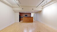 Located at 1 Page Ave in Asheville, NC, this 2-bedroom, 2-bathroom single-floor residence offers a thoughtfully designed layout that balances open communal spaces with comfortable private quarters. The expansive living and kitchen area serves as the heart of the home, featuring light hardwood flooring, track lighting, and exposed ductwork that lends an industrial character to the space. A central kitchen island anchors the room, complemented by warm wood cabinetry, dark granite countertops, black appliances including a refrigerator, built-in microwave, and dishwasher, and recessed lighting overhead. Plantation shutters and blinds throughout allow for flexible natural light control. The bedrooms are carpeted for comfort, with the primary suite offering generous proportions, a ceiling fan, and access to an en-suite bathroom via elegant French doors. The bathrooms are finished with white tile flooring and clean white vanities; one features a tub-shower combination with built-in shelving, while the other offers a streamlined vanity with a dark-framed mirror. Two closets and dual hallways provide practical storage and circulation throughout. The overall palette of warm neutrals and cream tones creates a bright, welcoming ambiance throughout the residence.