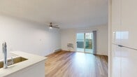 This 340 square foot studio apartment in Newport Beach offers a well-designed living space that maximizes efficiency and comfort. The single-floor layout features an open-concept design, seamlessly integrating the living area, sleeping space, and kitchen.

The apartment boasts beautiful hardwood flooring throughout, adding warmth and elegance to the space. A standout feature is the large sliding glass door, which floods the room with natural light and provides access to an outdoor area, potentially a small patio or balcony.

The kitchen, while compact, is modern and functional. It features stainless steel appliances, including a refrigerator and stove, and ample cabinet space in a light wood finish. A small island or peninsula separates the kitchen from the main living area, doubling as a dining or workspace.

The bathroom, though not extensively shown, appears to be clean and functional with a standard toilet and shower/tub combination. The apartment also includes practical amenities such as a wall-mounted air conditioning unit for climate control and a ceiling fan for air circulation.

Storage solutions are integrated into the design, with built-in cabinets visible in some areas. The neutral color palette, dominated by whites and light tones, contributes to a sense of spaciousness in this cozy studio. Overall, this apartment offers a comfortable and efficient living solution in a desirable Newport Beach location.