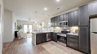 Located in San Marcos, TX, this thoughtfully designed one-bedroom, one-bathroom residence offers a comfortable and functional layout across a single floor. The open-concept living and kitchen area serves as the heart of the home, featuring light wood-style flooring that flows seamlessly throughout the space. The kitchen is appointed with dark espresso cabinetry, granite-style countertops, stainless steel appliances, and a peninsula island with bar seating, illuminated by pendant lighting above. The living room is bright and welcoming, with a ceiling fan overhead and French doors that invite natural light and provide outdoor access. The bedroom offers a cozy retreat, complete with a ceiling fan, a large window with outdoor views, and wood-style flooring accented by a woven area rug. Closet access and proximity to the bathroom ensure practical convenience. The bathroom is finished with light wood-style flooring, a dark-cabineted vanity with a granite-style countertop, and a full tub-shower combination with clean white surrounds. Neutral tones and soft lighting throughout the space create a warm, cohesive ambiance well-suited for everyday living.