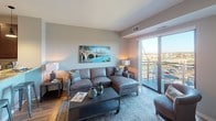 This single-floor residence offers a well-designed, open-concept layout that seamlessly connects the main living areas. The living room serves as a central gathering space, featuring warm hardwood flooring, neutral-toned walls, and a large sliding glass door that opens to a private balcony overlooking outdoor scenery, allowing abundant natural light to fill the room.

The kitchen is outfitted with rich, dark-stained cabinetry, light granite countertops, and a full suite of stainless steel appliances, including a refrigerator, electric range, and built-in microwave. A U-shaped layout maximizes workspace and storage, while the hardwood flooring continues the cohesive aesthetic from the living area.

The bedroom is a calm, carpeted retreat with neutral walls and a window providing natural light. It connects directly to a generously sized walk-in closet equipped with multi-tiered wire shelving for flexible storage. The bathroom features hardwood-style flooring, a dark-stained vanity with a light countertop, and a full tub-shower combination. Throughout the space, a consistent warm and neutral palette creates a cohesive, comfortable ambiance.