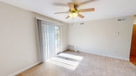 Located at 5529 Limerick Ln in Virginia Beach, VA, this single-floor, one-bedroom, one-bathroom home offers a well-designed layout that maximizes every inch of its compact footprint. The living room is bright and welcoming, featuring plush wall-to-wall carpeting, a ceiling fan with light fixture, and sliding glass doors that open to an outdoor balcony, allowing generous natural light to fill the space. The kitchen is a functional highlight, showcasing warm honey-toned wood cabinetry extending to the ceiling for ample storage, dark granite countertops, hardwood flooring, and a full suite of white appliances including a refrigerator, electric range, microwave, and dishwasher. A peninsula counter adds additional prep and dining space. The bedroom is comfortably sized, finished with soft carpet and a window framing views of the surrounding greenery. It features two interior doors — one leading to a dedicated closet and another connecting to the kitchen area. The bathroom is clean and straightforward, complete with a full soaking tub and shower combination with chrome fixtures. A utility room rounds out the functional spaces within the home, ensuring practical storage and household needs are met. Neutral tones throughout create a calm, move-in-ready atmosphere.