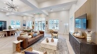 This 1,360 square foot single-story space showcases a contemporary open floor plan that seamlessly blends functionality with style. The heart of the space is a gourmet kitchen, featuring sleek gray cabinetry, stainless steel appliances, and a striking island with wood-paneled sides and comfortable bar seating. Adjacent to the kitchen, a spacious living area boasts high ceilings with recessed lighting and exposed beams, creating an airy atmosphere.

Large windows and glass doors flood the interior with natural light, offering views of the surrounding area. The living room is furnished with modern, comfortable seating, including a plush brown sofa and stylish wooden chairs. A unique coffee table serves as a focal point, complementing the area rug beneath.

The space's design incorporates natural elements, with light wood herringbone flooring throughout and wood accents on walls. Thoughtful decorative touches, such as potted plants, artwork, and sculptural lighting fixtures, add character to the space. A separate seating area near large windows provides a cozy nook for relaxation or reading.

The entryway features glass doors, maintaining the open feel and allowing ample light to penetrate the space. Overall, this modern, multifunctional space combines comfort and sophistication, ideal for both everyday living and entertaining guests.