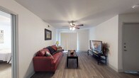 This single-floor residence offers a thoughtfully arranged layout that maximizes functionality across its living spaces. The living room serves as the focal point of the home, featuring durable wood-look flooring, a ceiling fan with integrated lighting, and a sliding glass door dressed with vertical blinds that allows natural light to fill the room. The space comfortably accommodates a seating area and entertainment setup.

Adjacent to the living room, the dining area provides an intimate setting with continued wood-look flooring and ample wall space for décor. The galley-style kitchen is outfitted with dark espresso cabinetry, white countertops, black appliances including a range and refrigerator, and light-toned flooring, creating a striking contrast throughout the space.

The bedroom offers plush carpeting underfoot, a ceiling fan, and a window that brings in natural light. A closet is accessible directly from the room, adding convenient storage. The bathroom includes a full-size soaking tub and shower combination with white subway tile surround, maintaining a clean and functional aesthetic.

Overall, the unit presents a cohesive, practical design with consistent finishes throughout, offering a comfortable living environment.