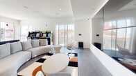 Located at 1530 Cassil Place in the heart of Hollywood, Los Angeles, this single-floor amenity space combines contemporary design with playful, retro-inspired elements. The open-plan lounge area serves as the centerpiece, featuring large-format tile flooring, crisp white walls, and an abundance of natural light pouring in through floor-to-ceiling sliding glass doors that open to views of the surrounding cityscape. The lounge is furnished with curved, modern seating, sculptural tulip-style chairs, and bold geometric-patterned area rugs that add visual energy to the space. Classic arcade machines line one wall, offering a fun, nostalgic touch, while a large mirrored window connects to an adjacent seating alcove, adding depth and dimension. A secondary lounge area features a built-in sofa and additional casual seating, ideal for gatherings or relaxed conversation. The kitchenette is well-appointed with light wood cabinetry, a stainless steel sink, dishwasher, compact refrigerator, and a striking geometric-patterned accent wall adorned with colorful artwork. A fully accessible restroom rounds out the space, featuring textured tile wainscoting, an orange vessel sink, and ADA-compliant fixtures. Throughout, the design strikes a balance between clean modernism and vibrant personality.