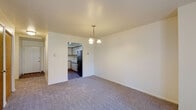 This two-floor townhouse at 6152 Independence Dr in Portage, Michigan offers a straightforward and functional layout across two levels. The main floor opens to a dining area finished with neutral carpet and accented by a pendant chandelier overhead. An open passage connects directly to the kitchen, which features hardwood-style flooring, cream cabinetry with wood trim detailing, and a full suite of black appliances including a range, over-the-range microwave, dishwasher, and refrigerator. A window above the sink allows natural light into the cooking space. The living area on the main floor is generously sized, with plush carpet and a sliding glass door that opens to an outdoor view of a grassy lawn flanked by trees, bringing in ample natural light. A half bath is conveniently located on this level, complete with a vanity and mirror. Upstairs, the bedrooms are carpeted and well-lit by large windows that provide views of the surrounding neighborhood. A full bathroom on the upper level includes a wood-trimmed vanity, overhead lighting fixture, and a shower-tub combination. Throughout the townhouse, the neutral color palette and clean lines create a calm, practical living environment.