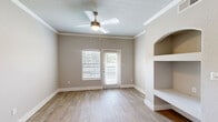 Located at 4699 Fossil Vista Dr in Haltom City, TX, this two-bedroom, two-bathroom residence offers a well-designed single-floor layout with thoughtful finishes throughout. The open-concept kitchen and living area serves as the heart of the home, featuring a peninsula with white quartz countertops, an undermount sink, and gray shaker-style cabinetry with gold hardware. Stainless steel appliances, including a refrigerator, dishwasher, range, and microwave, complete the kitchen. Wood-look flooring runs through the main living areas, complemented by crown molding and neutral-toned walls. The living room includes a ceiling fan, built-in arched shelving, and a door that opens to a private balcony overlooking manicured landscaping and the surrounding community. Both bedrooms are carpeted and offer a calm, neutral palette, with the primary bedroom featuring its own walk-in closet equipped with wire shelving. The two bathrooms are finished with marble-style tiled tub-surround enclosures, gray vanities with white countertops, and wood-look flooring. A dedicated hallway and closet add practical storage to this efficiently arranged home.
