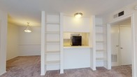 Located at 833 S University Blvd in Mobile, Alabama, this single-floor unit offers a thoughtfully designed layout with a variety of functional living spaces. The living area is a standout, featuring a unique built-in shelving unit flanking a pass-through kitchen window, creating a visually interesting and highly functional divider between the living and kitchen areas. Ceiling fans are present throughout the carpeted rooms, contributing to a comfortable atmosphere. The galley-style kitchen is efficiently laid out with ample white cabinetry lining both walls, light-toned countertops, wood-look flooring, and black appliances including a refrigerator, stove, and dishwasher. A double sink sits beneath a window, allowing for natural light. The bedrooms are generously sized with plush carpeting, ceiling fans, and large windows fitted with blinds that invite natural light. One bedroom includes a walk-in closet with built-in shelving for added storage. The living room opens to an outdoor area through a sliding glass door with vertical blinds, while the bathroom features a tiled tub-shower combination, wood-look flooring, and a white vanity with under-sink storage.
