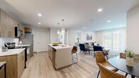 Located at 2305 Sokol Ct in Darien, IL, this thoughtfully designed one-bedroom, two-bathroom residence offers a modern, open-concept floor plan that maximizes functionality and style. Light wood-tone flooring flows throughout, complementing the clean white walls and recessed lighting that create a bright, cohesive ambiance.

The kitchen serves as a centerpiece of the living space, featuring warm wood cabinetry, a white subway tile backsplash, stainless steel appliances, and a striking quartz-topped island with seating — ideal for casual dining or entertaining. Globe pendant lights add an elegant finishing touch overhead.

Two distinct living areas provide flexible use of space. One is oriented around a wall-mounted flat-screen TV, while the other offers a more intimate lounge setting with natural light filtering in through vertical blinds.

The spacious primary bedroom accommodates generous furniture and includes a ceiling fan, natural light from a window with blinds, and light wood flooring — creating a calm, restful retreat.

Both bathrooms are finished with marble-look tile, including a full tub-shower combination in one, delivering a clean and contemporary aesthetic. A dedicated closet and an additional sitting nook round out this well-organized residence, making efficient use of every square foot.