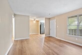 This single-floor unit is thoughtfully laid out to maximize its available square footage across three bedrooms, two bathrooms, a living room, kitchen, and hallway. Warm-toned walls in neutral taupe complement the rich hardwood flooring found throughout the main living areas, hallway, and bathrooms, while plush carpet adds comfort to each bedroom. Textured ceilings are consistent throughout the unit.

The living room is a generous open space featuring dark hardwood floors, a ceiling fan, and a window that allows natural light to filter in. An adjacent area with lighter hardwood flooring provides flexible use of space. The kitchen is equipped with dark espresso cabinetry, granite-style countertops, black appliances including a range and dishwasher, and a window above the double sink.

Each bedroom features carpet flooring, neutral walls, and closets with bifold doors. The primary bedroom includes direct hallway access and a built-in closet rod. One bathroom features a tub-shower combination with open shelving for storage, while the second bathroom includes a granite-topped vanity, hardwood floors, and a large storage closet.