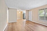 This single-floor unit is thoughtfully laid out to maximize its available square footage across three bedrooms, two bathrooms, a living room, kitchen, and hallway. Warm-toned walls in neutral taupe complement the rich hardwood flooring found throughout the main living areas, hallway, and bathrooms, while plush carpet adds comfort to each bedroom. Textured ceilings are consistent throughout the unit.

The living room is a generous open space featuring dark hardwood floors, a ceiling fan, and a window that allows natural light to filter in. An adjacent area with lighter hardwood flooring provides flexible use of space. The kitchen is equipped with dark espresso cabinetry, granite-style countertops, black appliances including a range and dishwasher, and a window above the double sink.

Each bedroom features carpet flooring, neutral walls, and closets with bifold doors. The primary bedroom includes direct hallway access and a built-in closet rod. One bathroom features a tub-shower combination with open shelving for storage, while the second bathroom includes a granite-topped vanity, hardwood floors, and a large storage closet.
