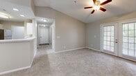 Located at 7959 Cottage Hill Rd in Mobile, Alabama, this single-story, three-bedroom, two-bathroom home offers a comfortable and functional layout. The open kitchen is a standout feature, equipped with stainless steel appliances including an electric range, over-the-range microwave, and refrigerator. Crisp white shaker cabinets, quartz-style countertops, and light wood-look flooring give the kitchen a clean, modern aesthetic that flows seamlessly into the living area. The living room showcases vaulted ceilings and a pendant light fixture, lending an airy, spacious feel to the common areas. The primary bedroom is generously sized and includes French doors that open to the outdoors, a ceiling fan, and plush carpeting. A dedicated walk-in closet with wire shelving provides ample storage. The secondary bedrooms also feature carpet, ceiling fans, and windows that bring in natural light with pleasant outdoor views. Both bathrooms are finished with white cabinetry, quartz-style countertops, and tub-shower combinations with white tile surrounds. Light wood-look flooring in the bathrooms adds a cohesive touch. A dedicated laundry room completes the practical layout of this well-appointed home.