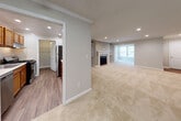 This single-floor residence offers a thoughtfully designed layout that balances open living spaces with practical functionality. The expansive main living area is carpeted and bathed in recessed lighting, featuring a fireplace flanked by built-in shelving that adds both storage and character. Large windows allow natural light to fill the room, enhancing its open and airy feel. An entryway with hardwood-style flooring provides a welcoming transition into the living space.

The kitchen is efficiently designed with warm wood cabinetry, a stainless steel gas range, ample counter space, and a pass-through window that connects it visually to the main living area. Adjacent to the kitchen is a dedicated walk-in pantry or laundry closet, adding convenient storage. Crown molding throughout the main living areas adds a refined architectural touch.

The bedrooms are carpeted and well-sized, offering generous closet space, including a sliding-door closet in one room and a walk-in closet in another. Multiple windows provide natural light and ventilation. The bathroom features a full tub-shower combination with clean white tile surround and classic chrome fixtures. Overall, the space presents a neutral, move-in-ready palette with consistent finishes throughout.