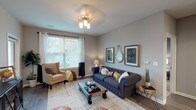 Unit 1105 is a thoughtfully designed single-floor residence that blends modern finishes with a warm, inviting atmosphere throughout. The living area is generously proportioned, featuring wood-style flooring, neutral gray walls, and a large window that fills the space with natural light and offers views of the surrounding exterior. A ceiling light fixture anchors the room, complementing the comfortable and functional layout.

The kitchen is a standout feature, showcasing dark espresso cabinetry, granite-style countertops with subtle veining, a classic white subway tile backsplash, and a full suite of stainless steel appliances including a refrigerator, range, and built-in microwave. A peninsula with an undermount sink provides additional prep space and casual seating.

The bedrooms are carpeted for comfort, with one featuring a walk-in closet and access to a well-appointed en suite bathroom. The primary bathroom includes dark cabinetry, granite countertops, and wood-style flooring, while a secondary bathroom offers a tub-shower combination. A welcoming entryway with wood-style flooring connects the living and kitchen areas, completing the cohesive and functional floor plan.