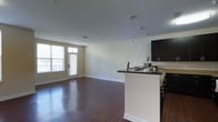 This two-floor residence at 2061/G offers a well-designed layout with modern finishes and a functional open-concept floor plan. The main living area is anchored by rich, dark hardwood flooring that extends throughout, providing a warm and cohesive aesthetic. Neutral-toned walls complement the space, creating a bright and versatile backdrop suitable for a variety of interior styles.

The kitchen is a standout feature, showcasing dark espresso cabinetry paired with dark countertops along a peninsula that seamlessly connects the kitchen to the living area. Elegant pendant lights hang above the peninsula, adding a contemporary touch and enhancing the kitchen's visual appeal. Stainless steel appliances and ample cabinetry provide both style and practicality.

The open living area benefits from natural light streaming in through large windows and a glass-paneled door that leads to an outdoor space, further brightening the interior. Smooth ceilings with recessed lighting contribute to the clean, modern aesthetic found throughout. Spanning two floors, this residence offers distinct living zones, providing comfortable separation between common areas and private spaces, making it a well-rounded and thoughtfully designed home.
