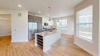 Located at 8801 Old Hickory Trail in Dallas, TX, this thoughtfully designed 2-bedroom, 2-bathroom residence offers a comfortable and modern living experience across a single floor. Light wood-look flooring flows consistently throughout the space, lending warmth and visual continuity to every room.

The kitchen serves as a central highlight, featuring a large granite-topped island with a built-in sink and wine rack, pendant lighting, stainless steel appliances, and a combination of white upper cabinets and dark wood-toned lower cabinets with a classic tile backsplash. Natural light pours in through large windows that overlook the surrounding green areas.

Both bedrooms are bright and well-sized, each equipped with ceiling fans and generous closet space. The primary bedroom includes a walk-in closet with ample shelving and direct access to a private en-suite bathroom. The bathrooms are finished with granite vanity countertops, framed mirrors, and modern fixtures. The primary bath features a soaking tub and tiled shower surround.

Each bedroom also benefits from direct outdoor views. The covered front patio provides additional outdoor living space overlooking a manicured lawn enclosed by a metal fence, creating a welcoming and private outdoor retreat.