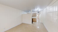 Located at 5550-5502 Washington St in Hollywood, Florida, this one-bedroom, one-bathroom unit offers a clean, efficiently designed layout across a single floor. The interior is unified by large-format polished ceramic tile flooring throughout, reflecting light and lending a bright, cohesive feel to the space.

The open living area is spacious and versatile, featuring white walls, a contemporary chandelier-style light fixture, and a semi-open connection to the kitchen via a partial partition wall. The kitchen has been thoughtfully updated with flat-front light wood cabinetry, white quartz countertops, a matte black single-basin sink, and stainless steel appliances including a refrigerator, range, and dishwasher — providing both style and functionality.

The bedroom is generously proportioned, offering a large double-door closet with raised-panel doors and a window that brings in natural light and outdoor views. The layout accommodates a variety of furniture arrangements comfortably.

The bathroom features a full tub-shower combination with floor-to-ceiling white square tile, a matte black showerhead, and chrome fixtures, giving it a clean, classic appearance.

Overall, the unit presents a well-maintained, move-in ready space with modern updates and a neutral palette suited to a range of interior styles.
