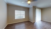 This single-floor residence offers a cohesive and functional layout finished with warm wood-look flooring that flows consistently throughout every room. The open living area is bright and welcoming, featuring crown molding, a ceiling fan with light fixture, and access to an outdoor area via a sliding glass door dressed with vertical blinds. Natural light filters in through horizontal blinds on the windows, lending a comfortable ambiance to the space.

The kitchen is well-equipped for everyday living, outfitted with dark espresso cabinetry, white countertops, a subway tile backsplash, and a full suite of stainless steel appliances including a refrigerator, range, microwave, and dishwasher. Conveniently adjacent to the kitchen is a dedicated laundry area housing a full-size washer and dryer alongside a water heater, keeping all utilities neatly contained.

The bedroom is generously sized, also featuring a ceiling fan and natural light from a window. It includes access to a walk-in closet with built-in wire shelving, offering ample storage. The bathroom is clean and simply appointed, with a tiled tub-shower combination, brushed nickel fixtures, and a toilet, maintaining the neutral, modern palette found throughout the home. The overall design is understated and move-in ready.